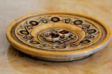 Two beautiful wedding gold rings on wooden plate. Marriage and details
