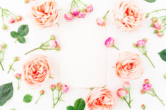 Floral round frame with pink roses and paper card on white background. Flat lay, top view. Flowers background. 