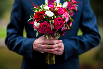 Groom hand holding wedding bouquet fresh flowers close up