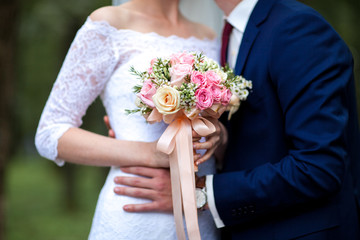 Obraz na płótnie Canvas Bride and groom hands holding wedding bouquet. Marriage concept.