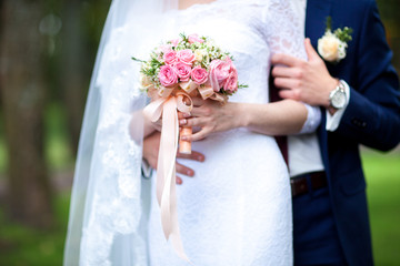 Bride and groom hands holding wedding bouquet. Marriage concept.