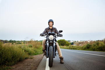 Young handsome man riding on motorbike at countryside road.