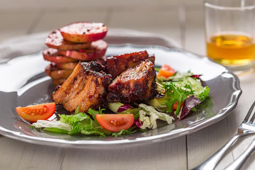 Hot Meat Dishes. Pork ribs grilled with salad and apples on a plate.