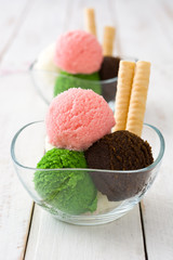 Ice cream scoops in crystal bowl on white wooden background. 
