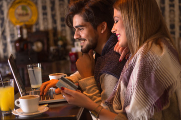 Beautiful young couple in cafe with laptop, shopping online.