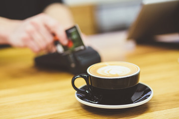 Paying for coffee. Close-up portrait man paying for cuppuccino with payment terminal. Barista making payment for service with terminal server.