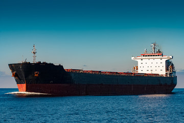 Black cargo ship moving in still Baltic sea water. Riga, Europe