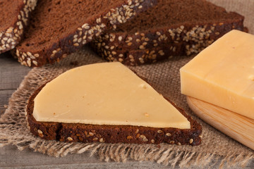 slices of black bread with sesame seeds and cheese on the old wooden background