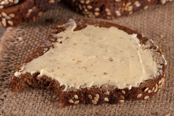 slices of black bread with sesame seeds and butter on an old wooden background