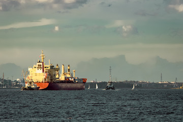 Red cargo ship and the tug ship towing  it to the port