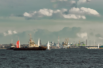 Tug ships and sailboats against cargo terminal in Riga