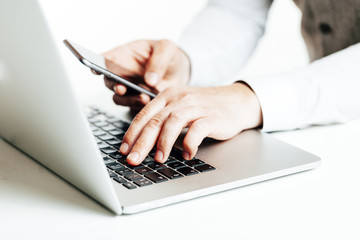 Close up image of multitasking business man using  a laptop and mobile phone