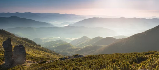 Fototapeten Panoramic landscape of the mountains at sunrise.  View of foggy hills and rural village. © vovik_mar