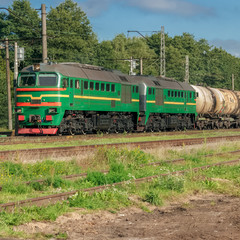 Obraz premium Freight train with tank wagons moving in forest. Green diesel ca