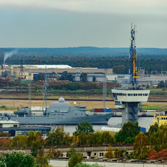 Military ship sailing past the cargo port in Riga, Latvia