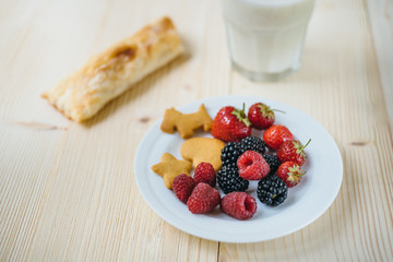 Rustic healthy breakfast with blueberry, raspberry, crackers, small loaf and milk in a glass on a wooden table. Healthy breakfast with vital vitamins.