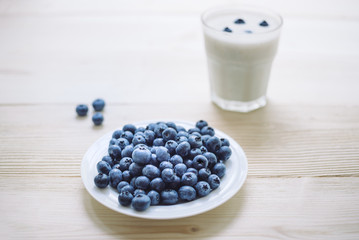 Rustic healthy breakfast with blueberry and yogurt in a glass on a wooden table. Glass of homemade yogurt with ripe berries. Healthy breakfast with vital vitamins.