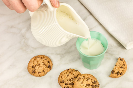 Milk poured into glass, with chocolate chips cookies