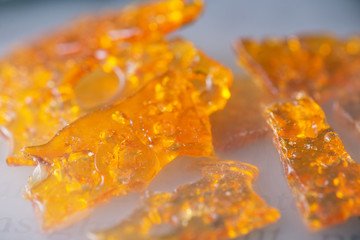 cannabis oil concentrate aka shatter pieces over smoky background - used by medical marijuana...