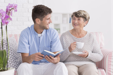 Professional carer reading to senior