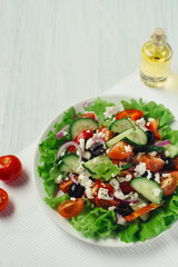 Greek salad with olive oil and tomatoes on white table top