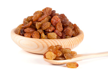 raisins in a wooden bowl with spoon isolated on white background
