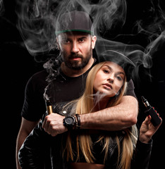 Brutal man and sexy woman are vaping. Studio shooting.