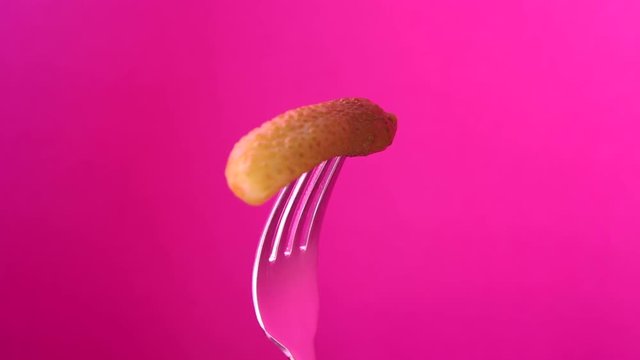 rotating fork with gherkin on pink background

