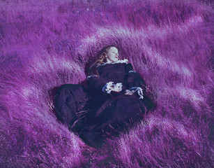 Fotografía artística de una chica con un vestido antiguo tumbada en un campo de hierba morada  © nanihta