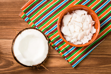 Мякоть кокоса в чаше и половина кокоса на деревянном столе