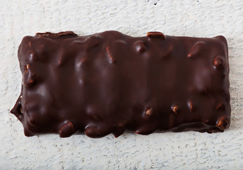 Chocolate candy with peanuts on an old wooden background.