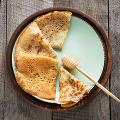 Tasty traditional russian breakfast of pancakes with honey on plate. Rustic style. Space for your text.