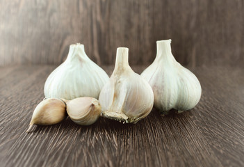 Obraz premium Garlic bulb and single cloveson wood background with shadow