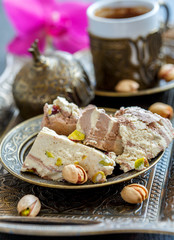 Tahini halva with cocoa and pistachio nuts closeup on a bronze plate.