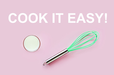 Neon greenery culinary whisk and glass of milk still life on a pink background.  Cook It Easy quote, inspirational poster