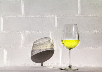 Glass of white wine against white brick wall.