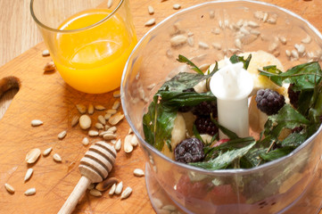 cooking, orange juice, banana,frozen strawberries blackberries and seeds vivid smoothie ingredients in blender, juicer, tulips on the background