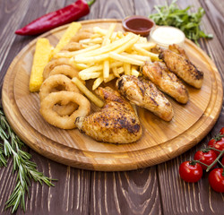 French fries with chicken wings on a wooden board
