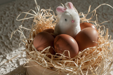 Easter rabbit inside a sieve full of easter eggs on rustic wood