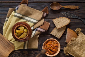 Baked potatoes in a clay pot, bread and sauce on a wooden table