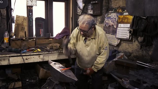 Blacksmith working on metal on anvil