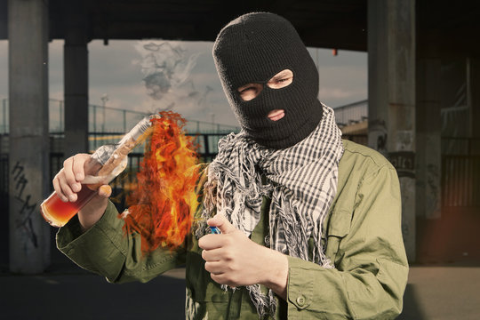 Anarchist in balaclava lighting molotov cocktail glass bomb