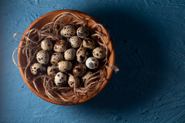 quail eggs in wooden bowl isolated on blue background close up