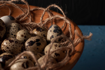 quail eggs in wooden bowl isolated on blue background close up