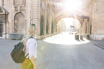 Portrait of beautiful young woman walking on the streets and exploring the city with backpack.