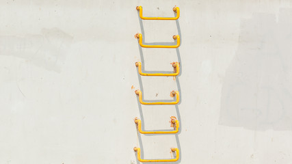 Yellow ladder on light grey conrecete wall