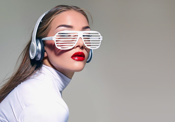 A beautiful girl in white glasses with big white headphones and loose hair, listening to music.
A...