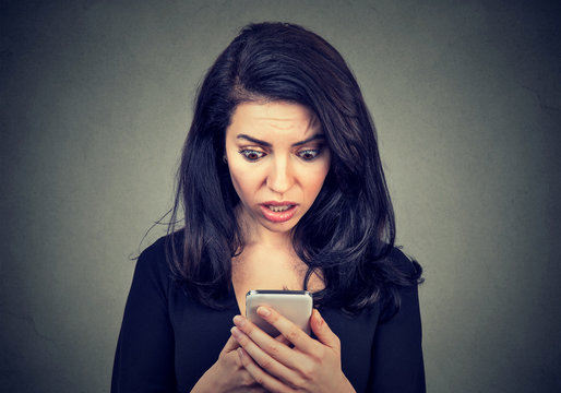 Shocked woman looking at cellphone worried with bad message news she received