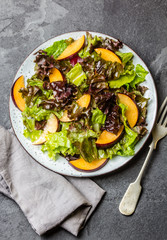 Vegetarian vegan lettuce salad with plums on black slate background. Top view