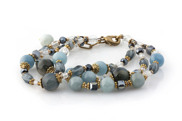 Bracelet made of natural stones and gold accessories on a hand on a white background